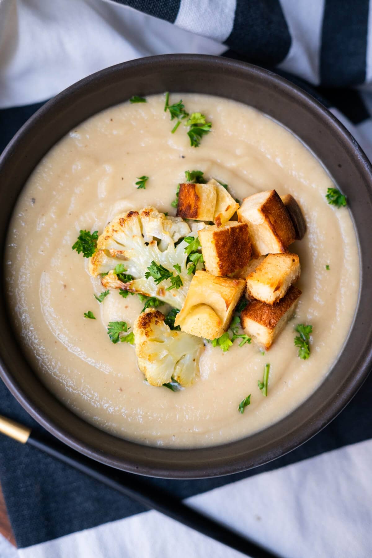 Roasted creamy cauliflower soup in a bowl with fork on the side. 