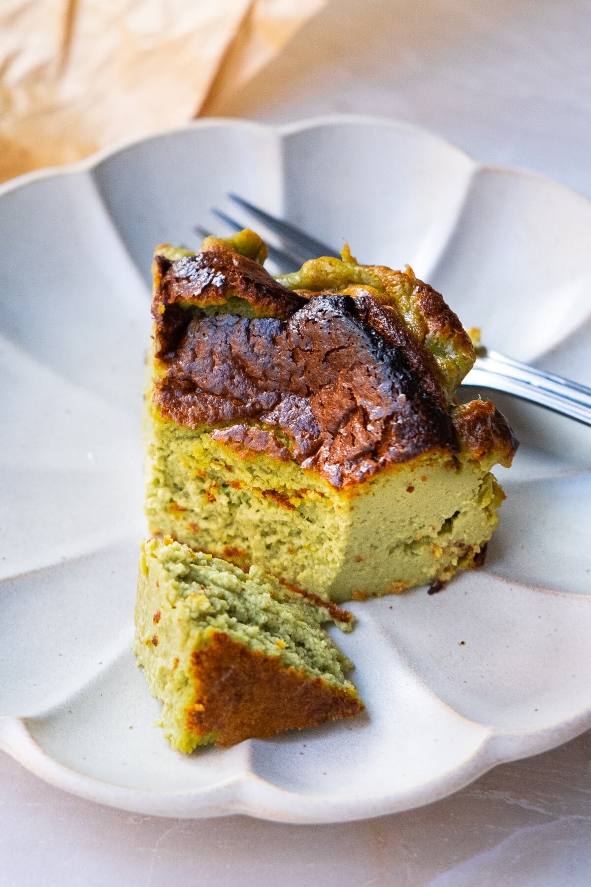 A slice of perfectly baked fluffy green on the inside crispy golden brown on the outside cheesecake. 