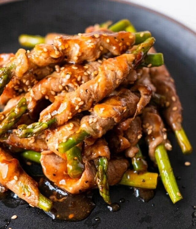 Hot pork wrapped asparagus served with white sesame on top.