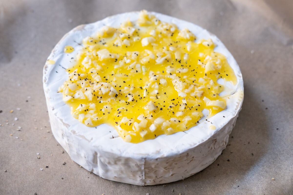 Melted butter, garlic, salt, ground black pepper and fresh thyme leaves spread evenly on top of the brie. 