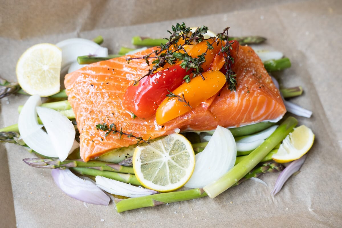 Place the vegetables on the parchment paper and add salmon fillet on top. 