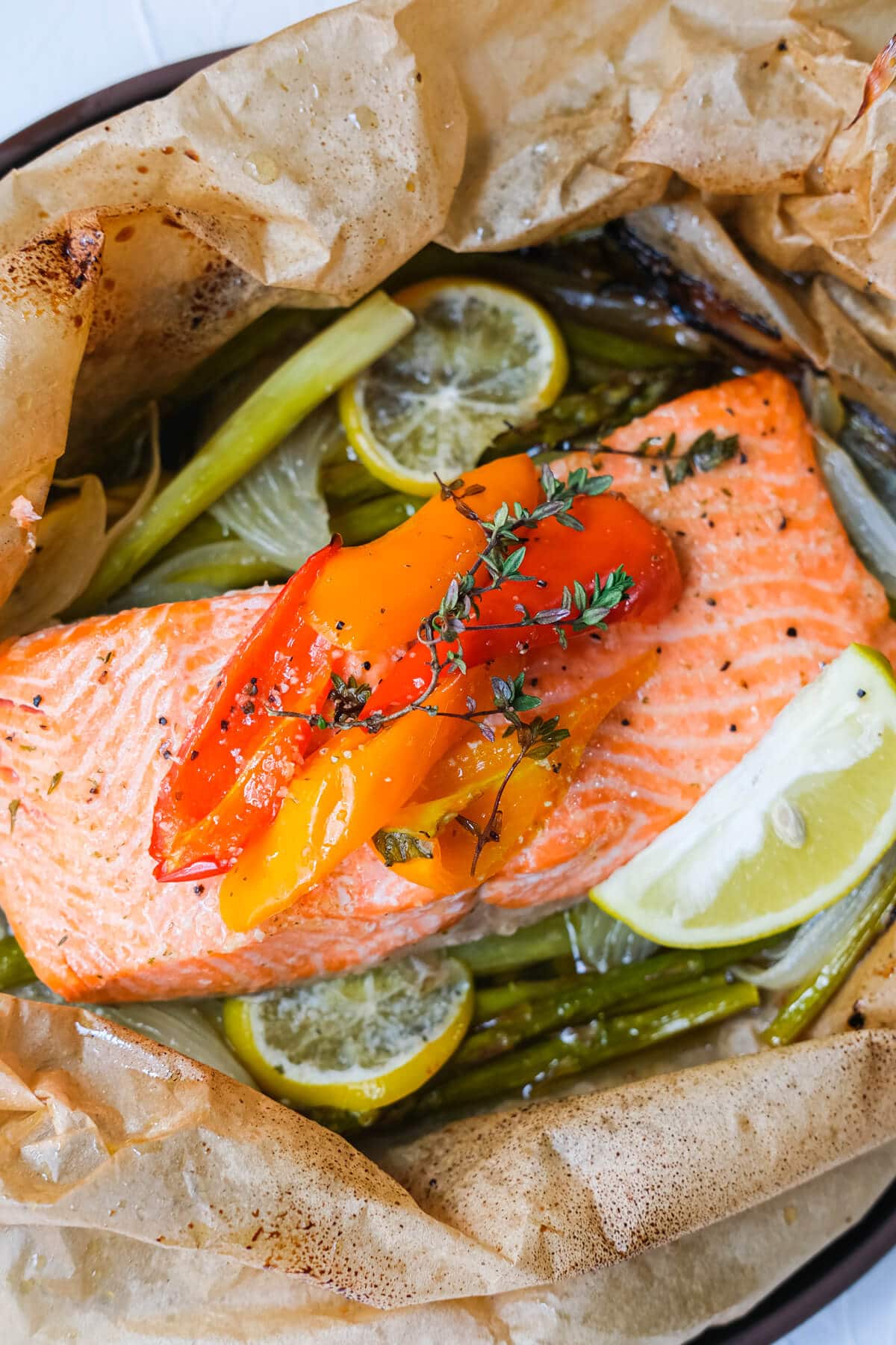 Thyme butter salmon parcels on the parchment paper and served with lemon wedges. 