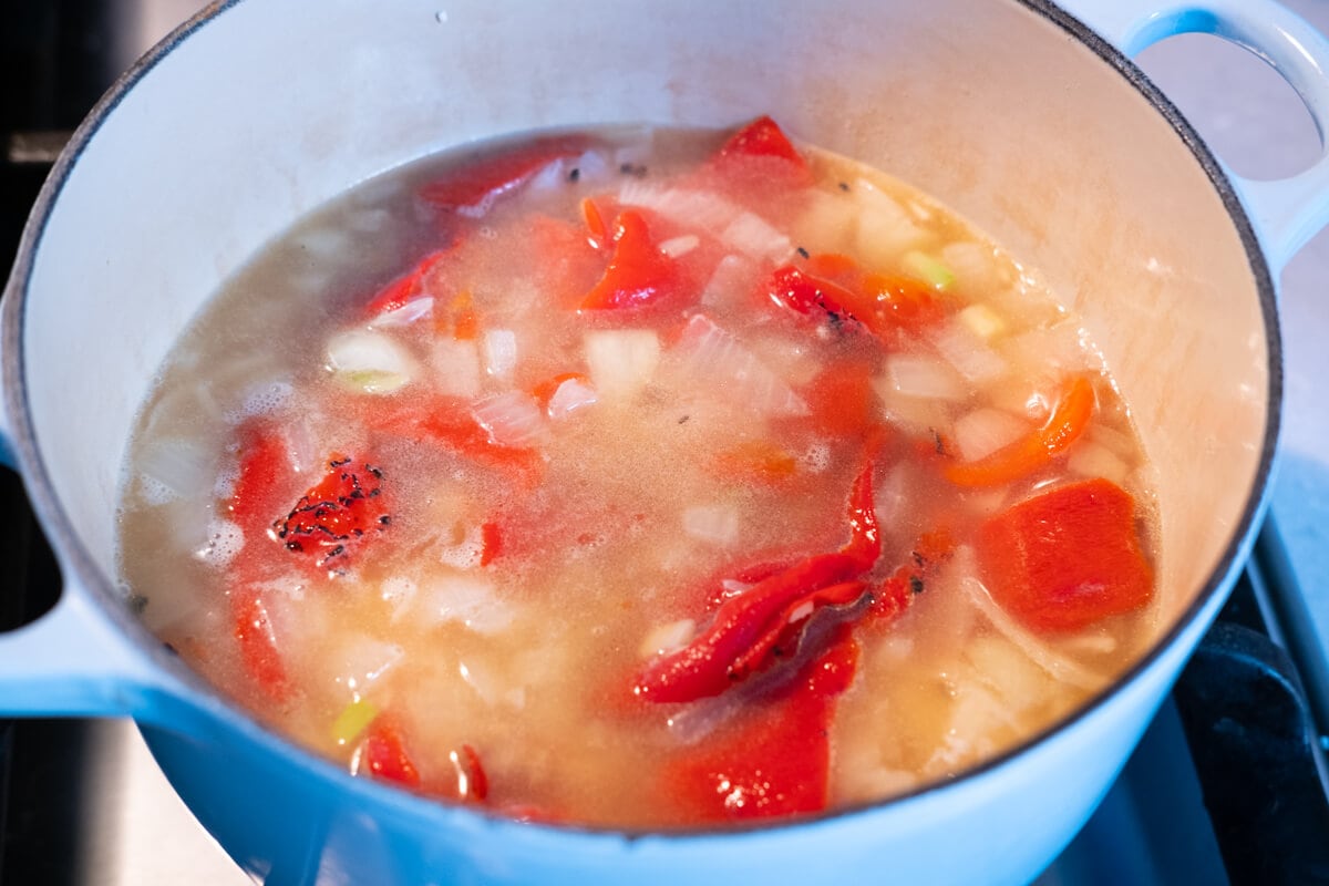 Mixture of rice, onion, garlic, roasted red pepper and chicken stock boiled in a pot. 