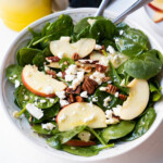 Spinach salad combined with apple slices, pecans and feta crumbles.