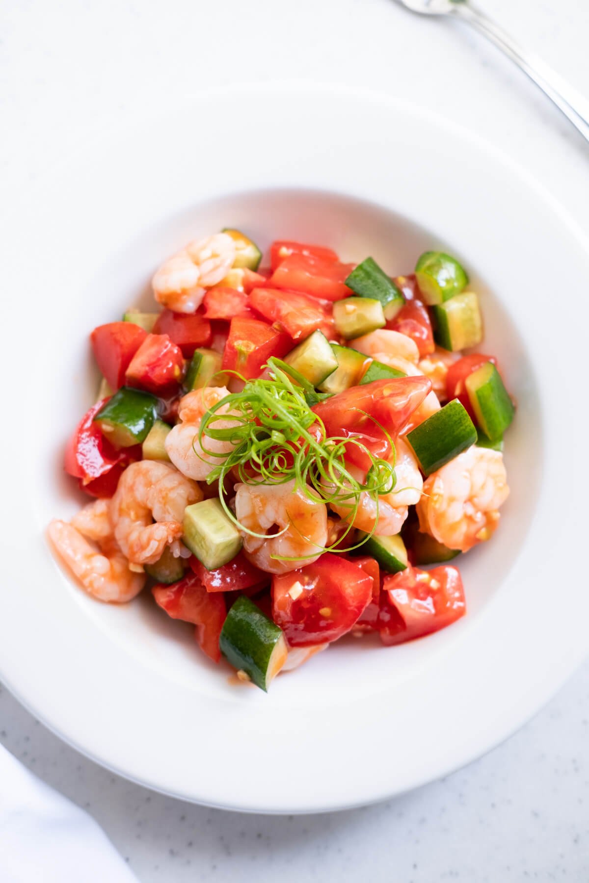 Refreshing tomato and shrimp salad served in a white shallow bowl. 