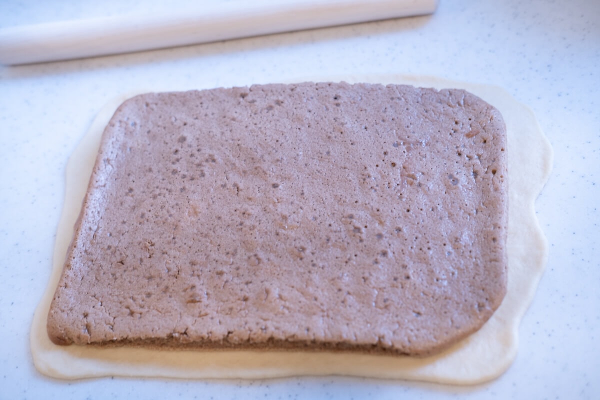 Bread dough rolled out into a rectangle with chocolate cake placed on top.