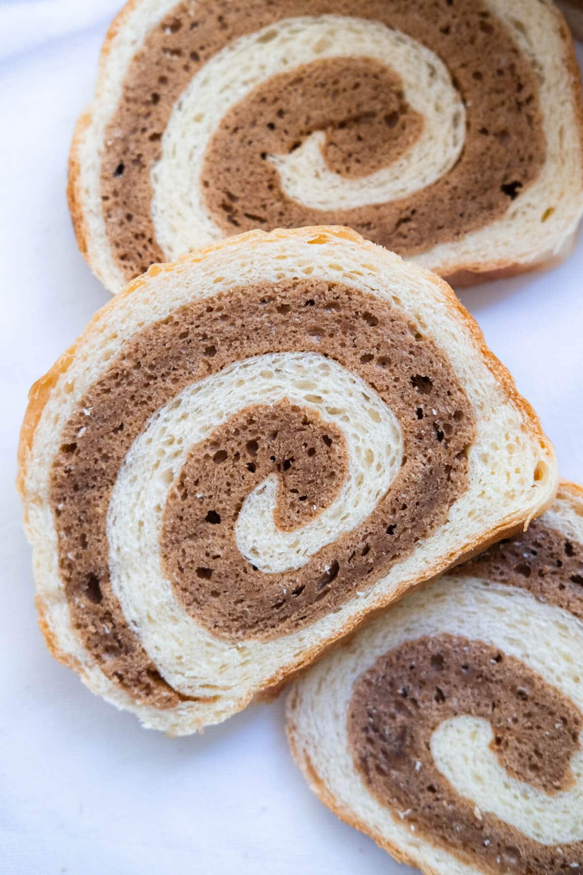 Slices of white bread with chocolate cake in between in swirling pattern. 