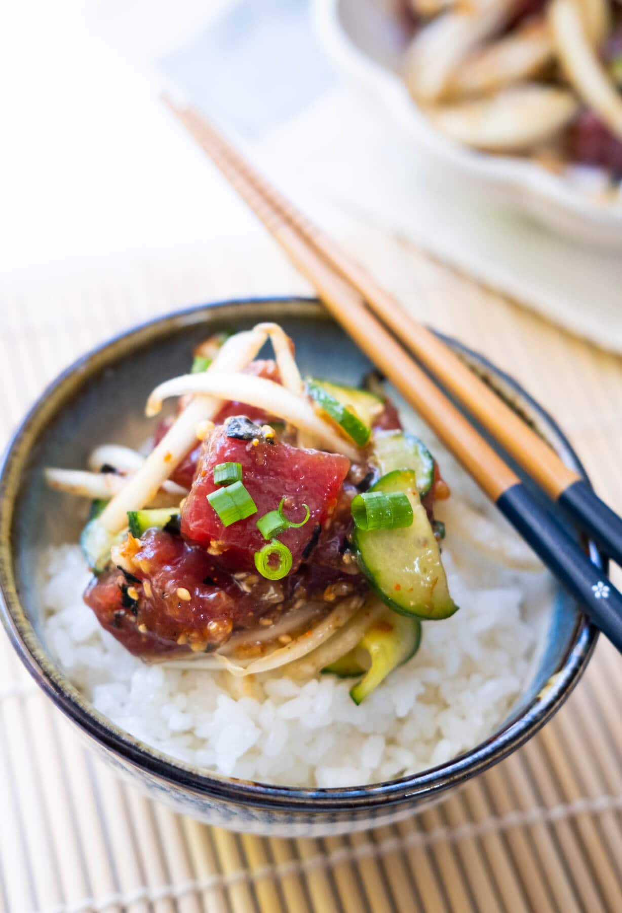 Fresh tuna coated with umami sauce and Japanese cucumber on top of white rice in a bowl. 