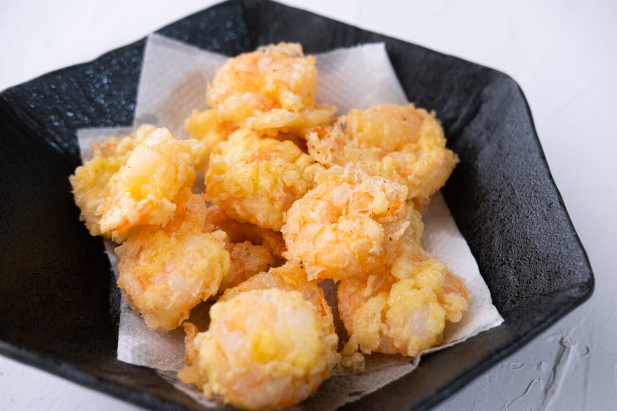 Deep-fried golden brown and crispy shrimp in a bowl lined with paper towel. 