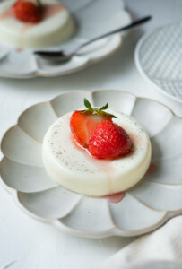 Smooth and creamy panna cotta on the plate with strawberry on top.