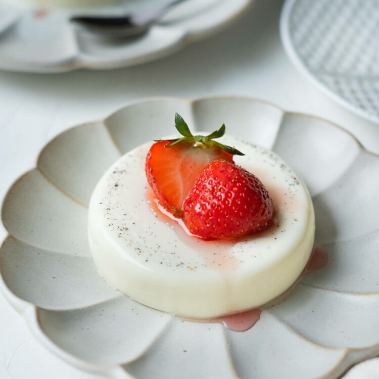 Smooth and creamy panna cotta on the plate with strawberry on top.