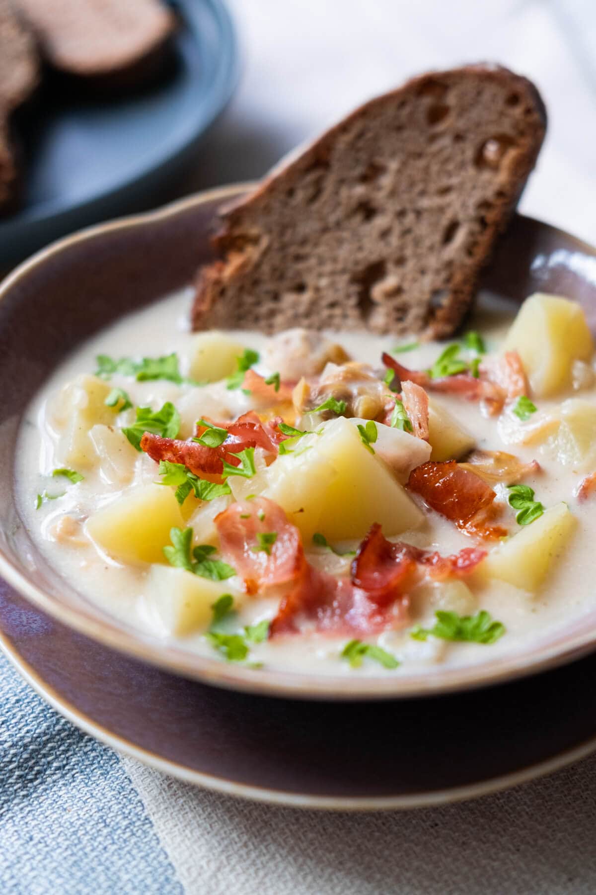 Delicious soup sprinkled with crispy bacon and potato inside with bread half dipped in a soup bowl. 