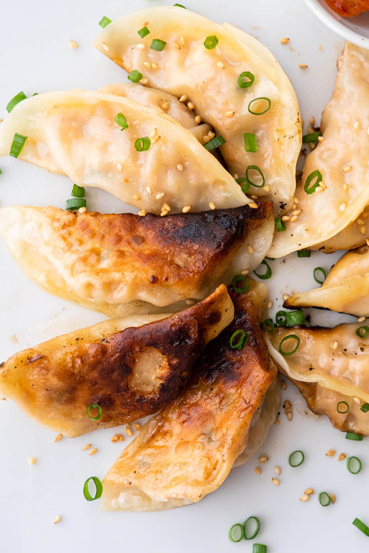 Pan-fried mandu with crispy bottom sprinkled with white sesame and scallions. 
