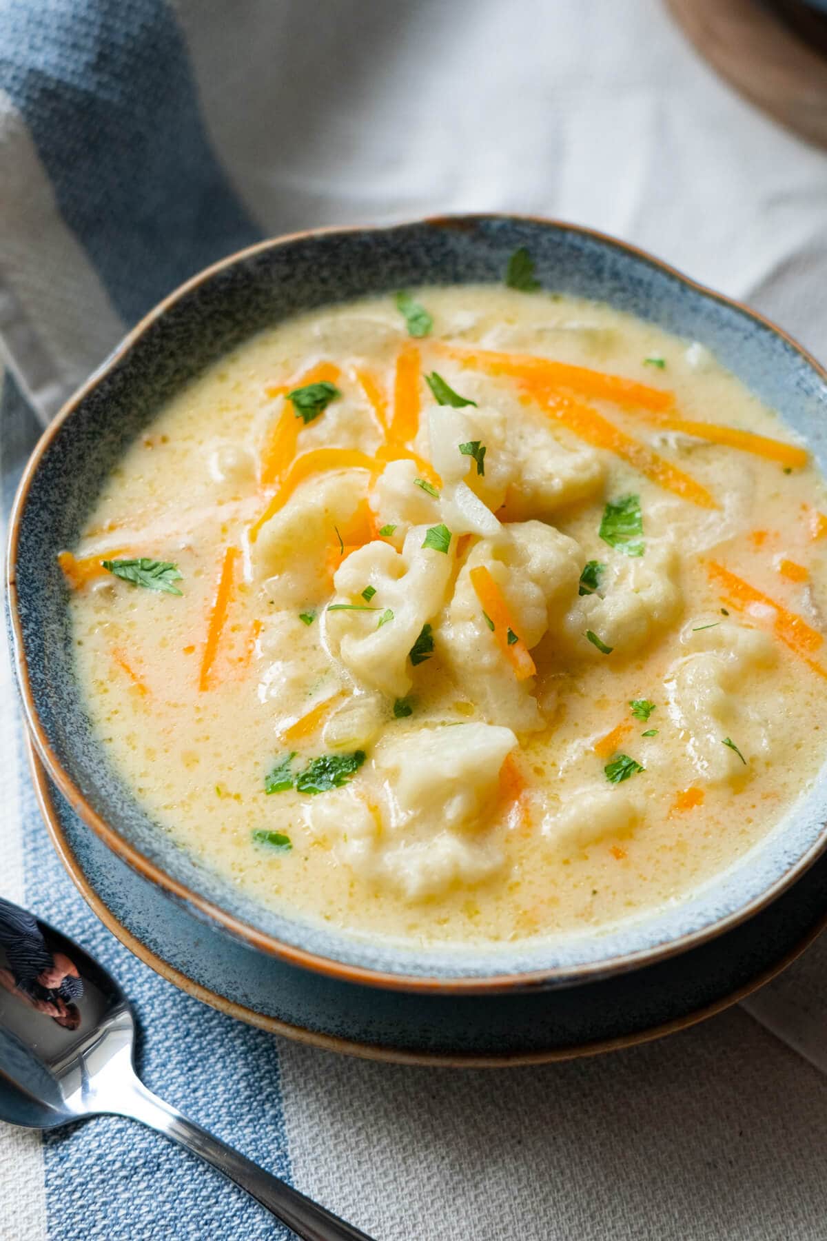 Creamy cauliflower soup is served with chopped parsley. 