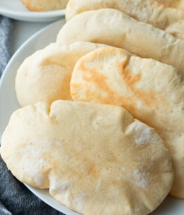 Puffy pita bread on a shallow plate.