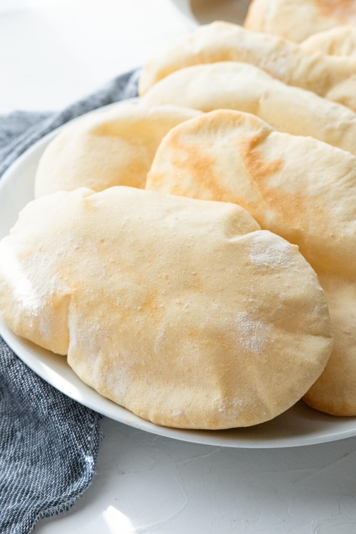 Soft pita breads with a slightly browned crust served on a plate. 