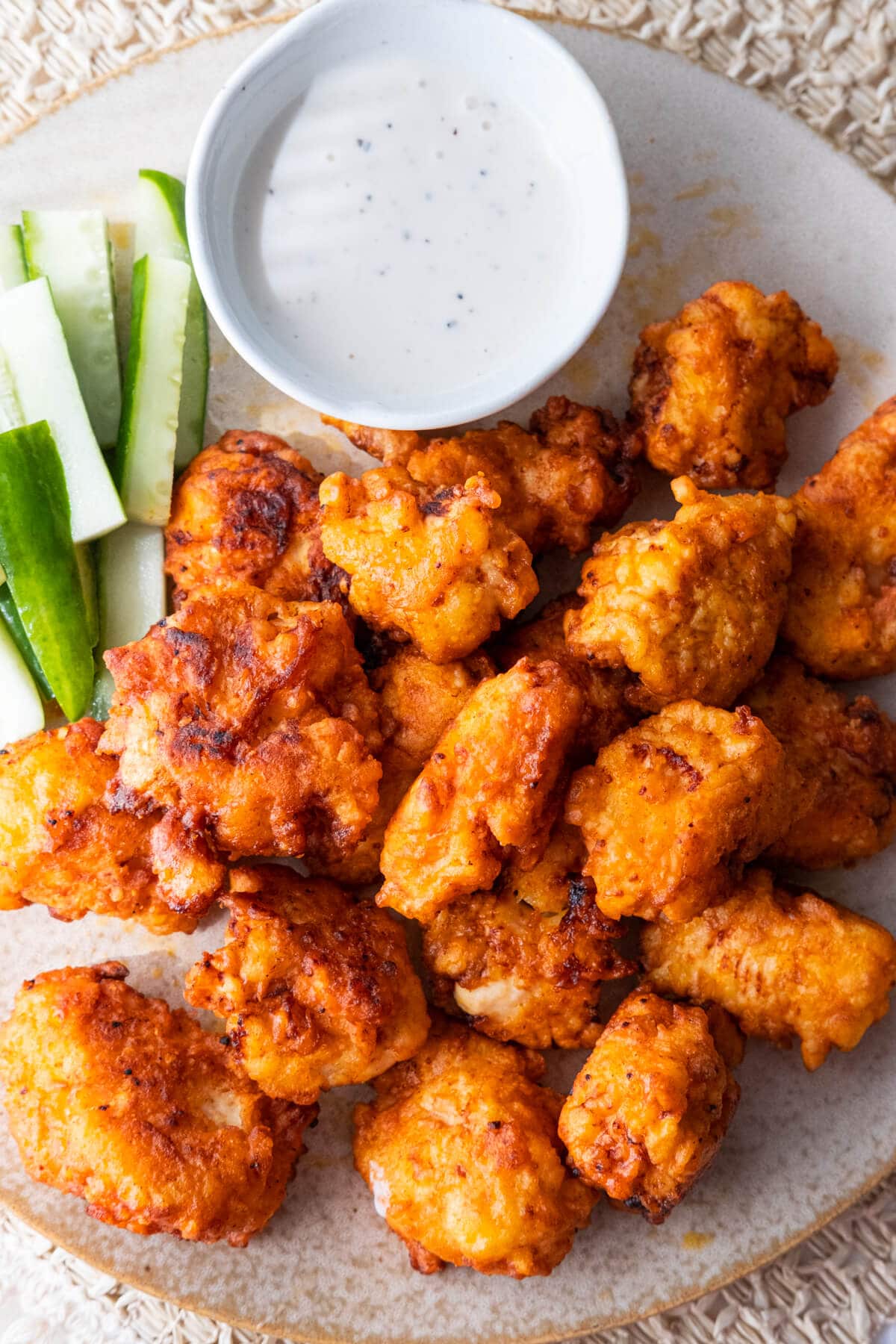 Delicious buffalo chicken bites coated with red, spicy buffalo-style sauce and served in a shallow plate. 