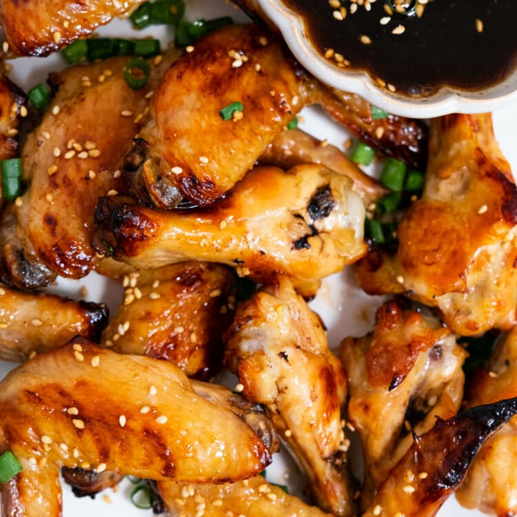 Coca-Cola chicken wings coated with sauce and garnished with chopped green onion.