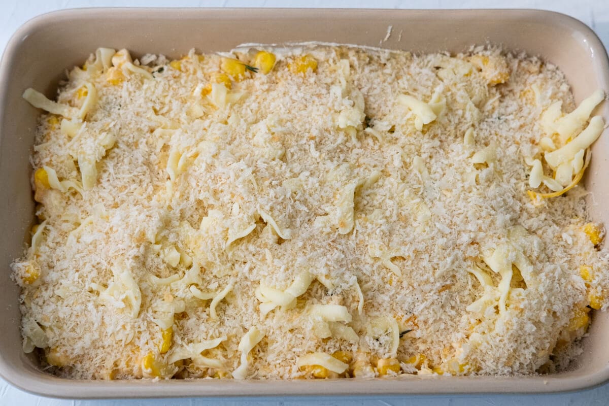 Corn mixture with mozzarella cheese and bread crumbs on top in a baking dish. 