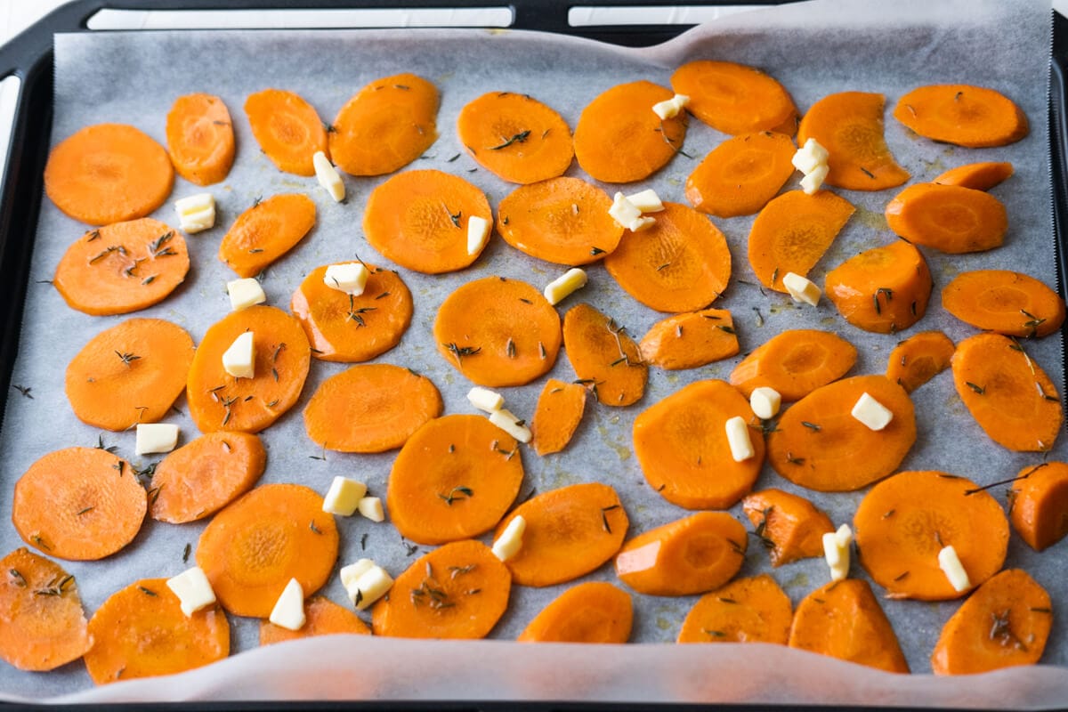 Arrange carrot slices on the baking pan lined with parchment paper and dot with butter. 