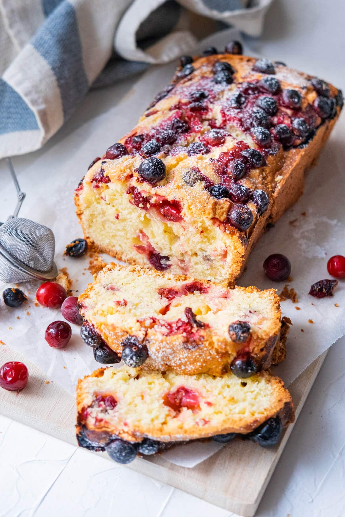 Moist and flavorful cake filled with cranberries on a serving board and sliced. 