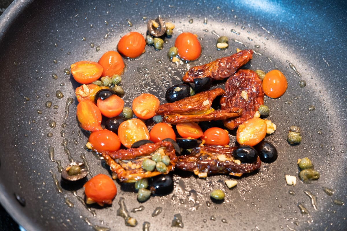 Sauté fresh cherry tomato halves, pitted black olive halves, sun dried tomato slices, garlic, capers in a skillet.  