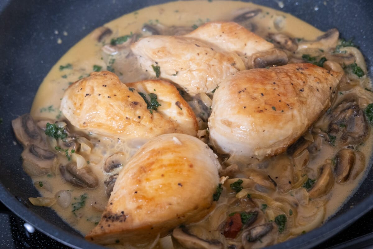 Cooked chicken breasts in the skillet coated with creamy mushroom sauce. 