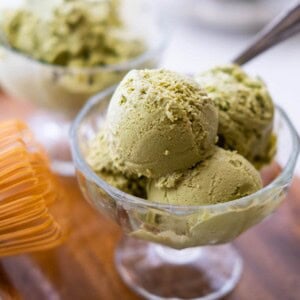 Two glass cups fill with match ice cream on a wood plate.