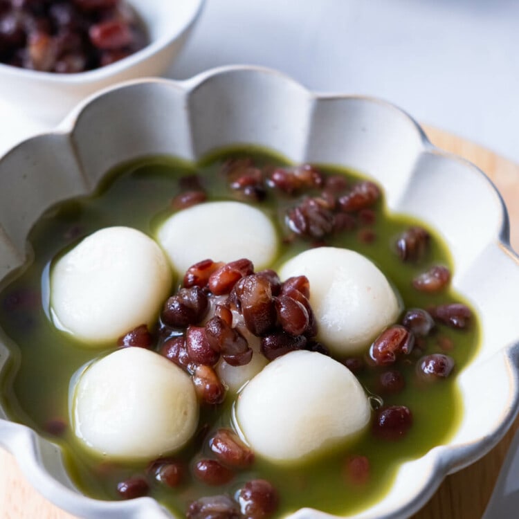 A bowl of sweet red bean soup with glutinous rice flour dumplings and matcha tea.