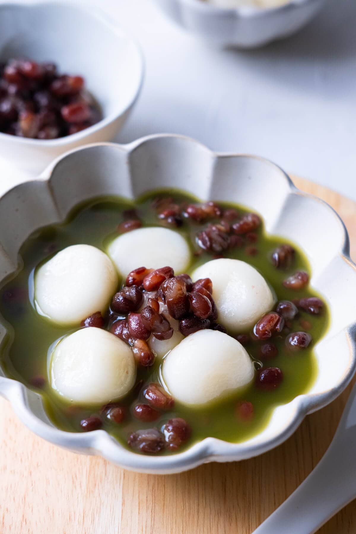 A bowl of sweet red bean soup with glutinous rice flour dumplings and matcha tea.