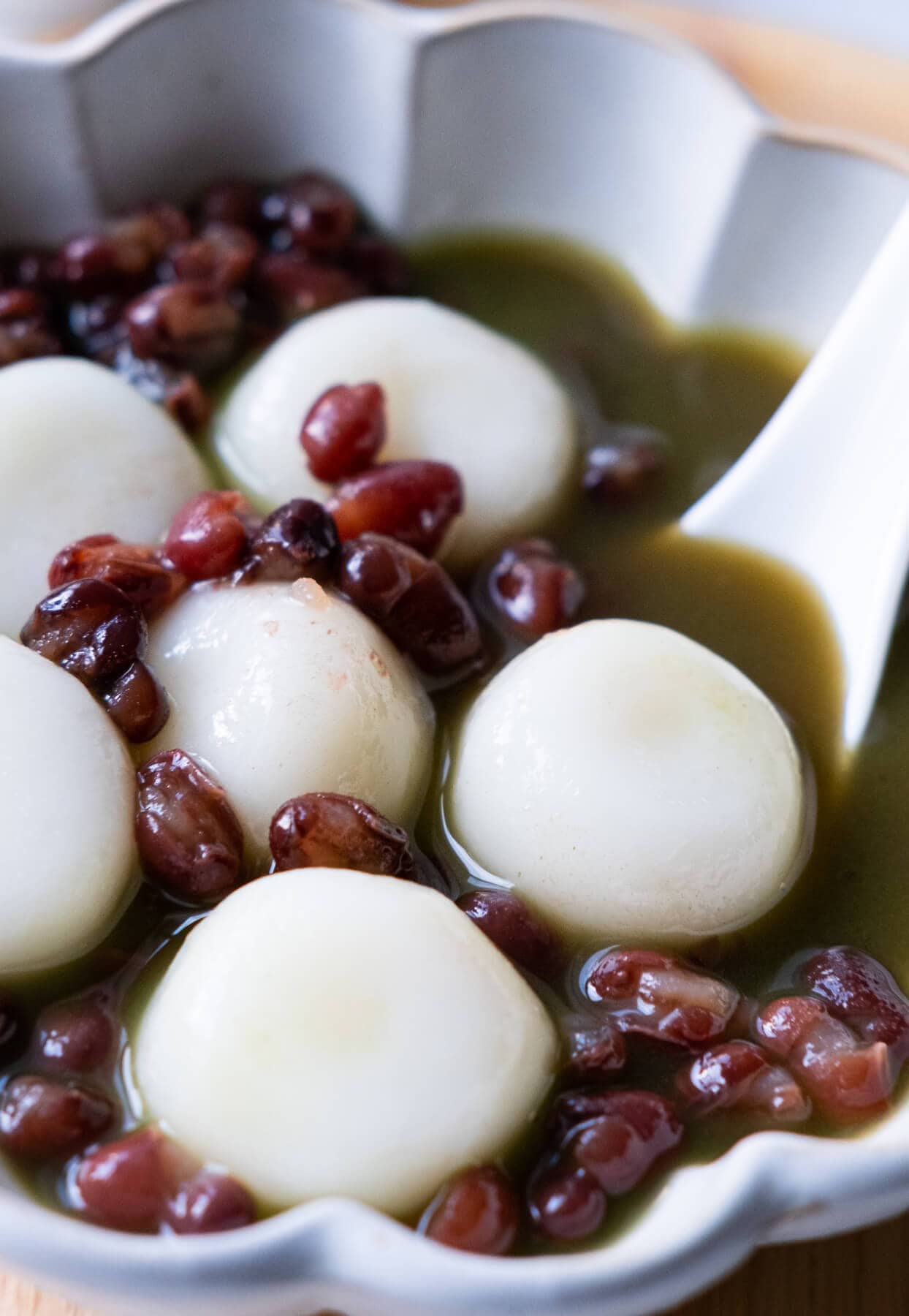 Close up on small white dango with red bean soup in a bowl. 