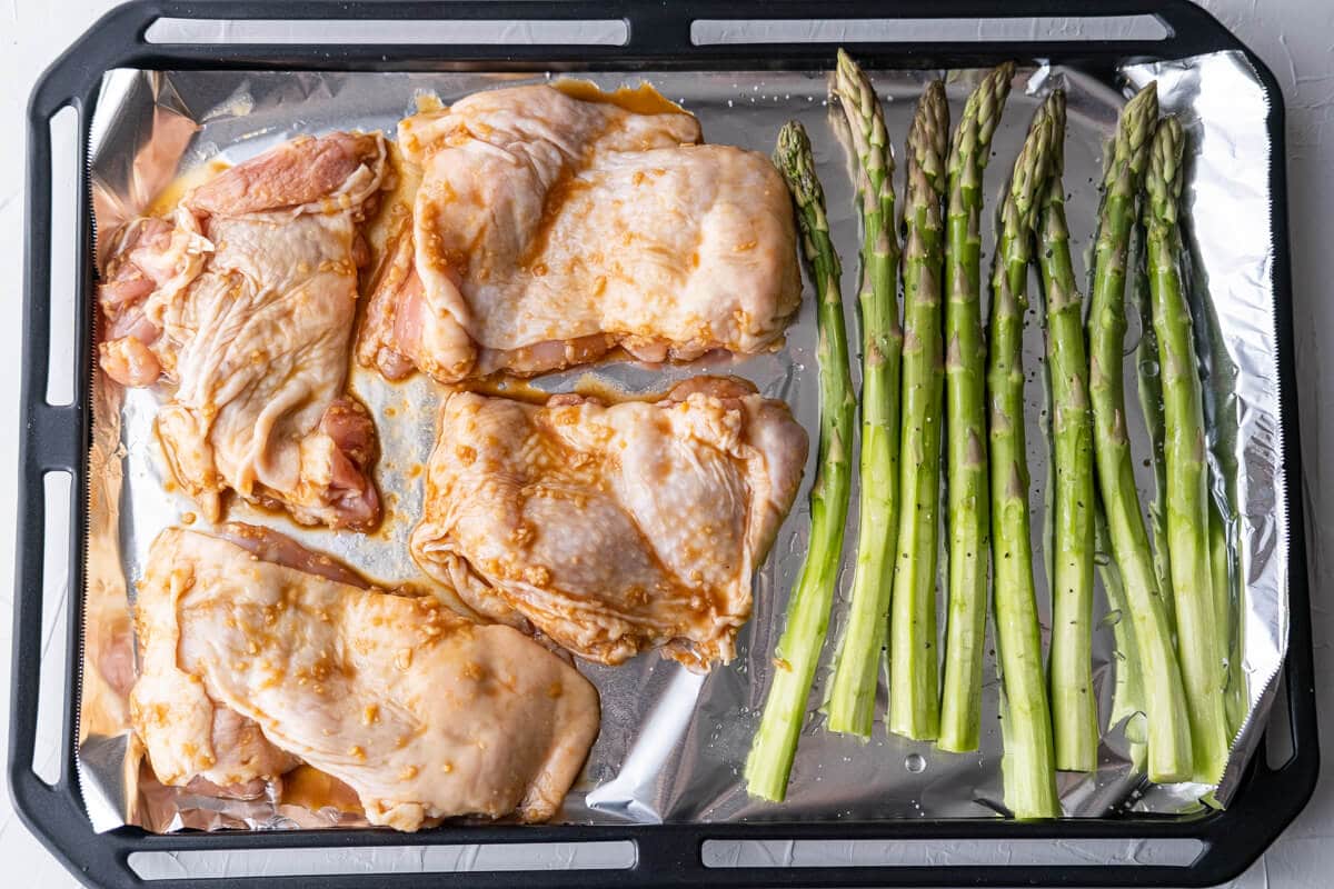 Arrange the chicken thighs and asparagus in a single layer on the baking pan lined with aluminum foil. 