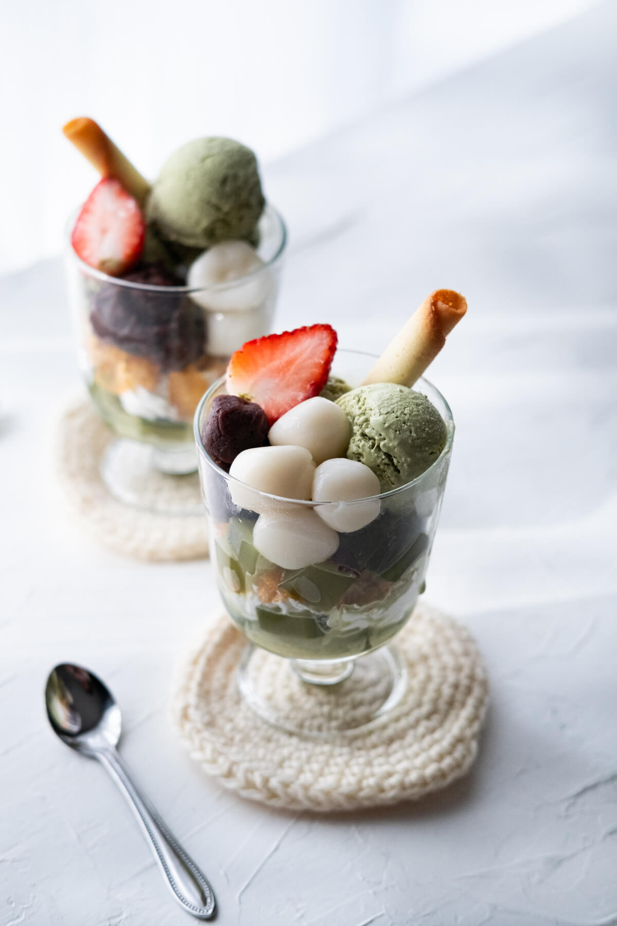 Matcha parfait layered with whipped cream, matcha jelly, mochi, sweet red bean paste, and topped with matcha ice cream, strawberry and cookie.