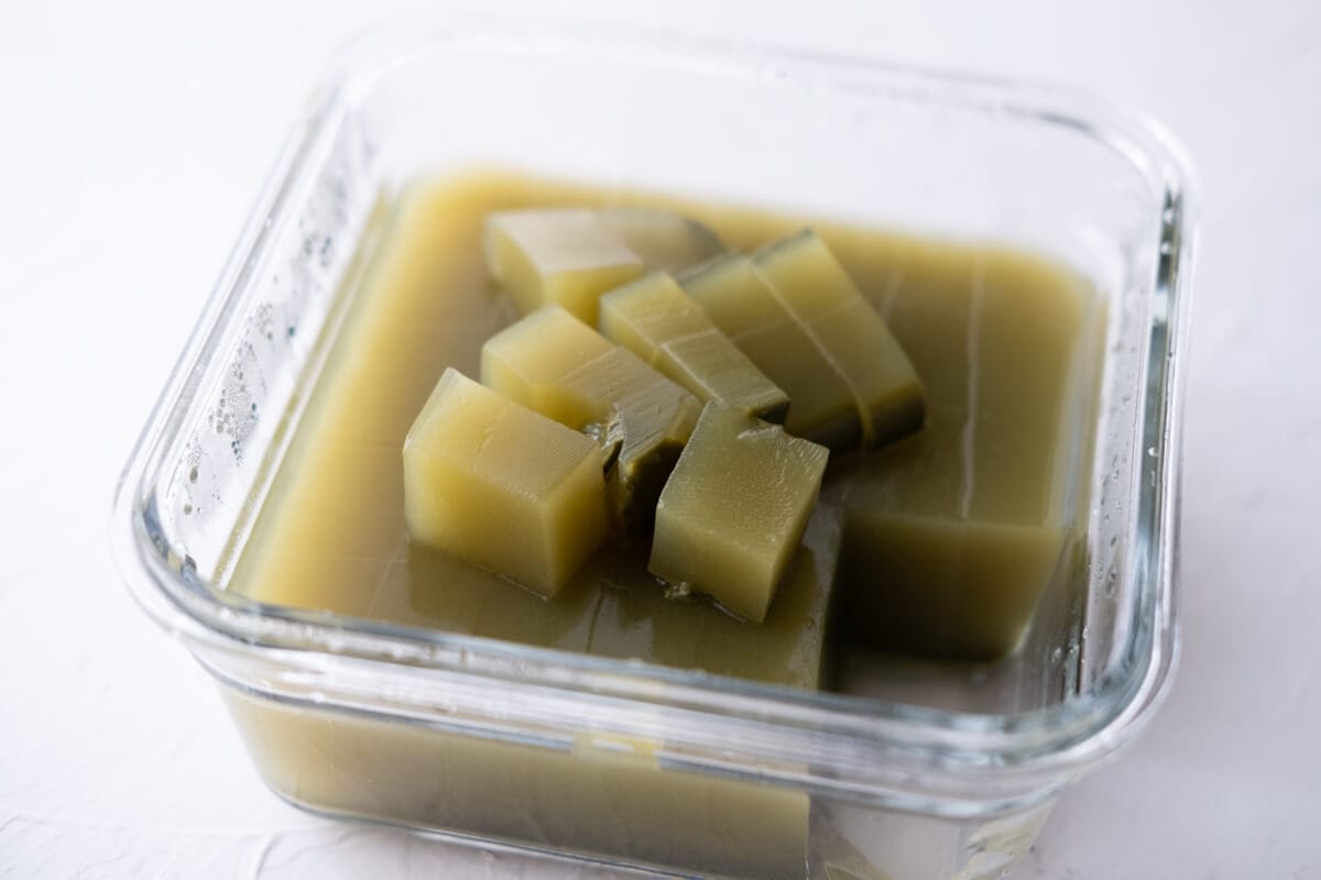 Bite-sized matcha jelly cubes in a glass container. 