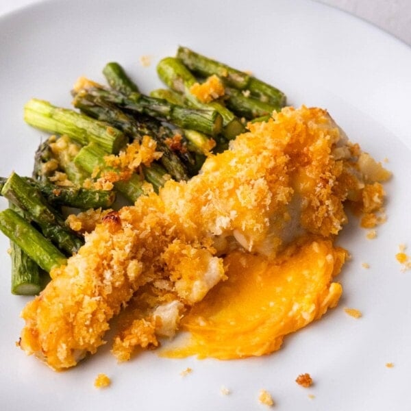 Baked sea bass fillet with golden brown crispy panko on top alongside asparagus.