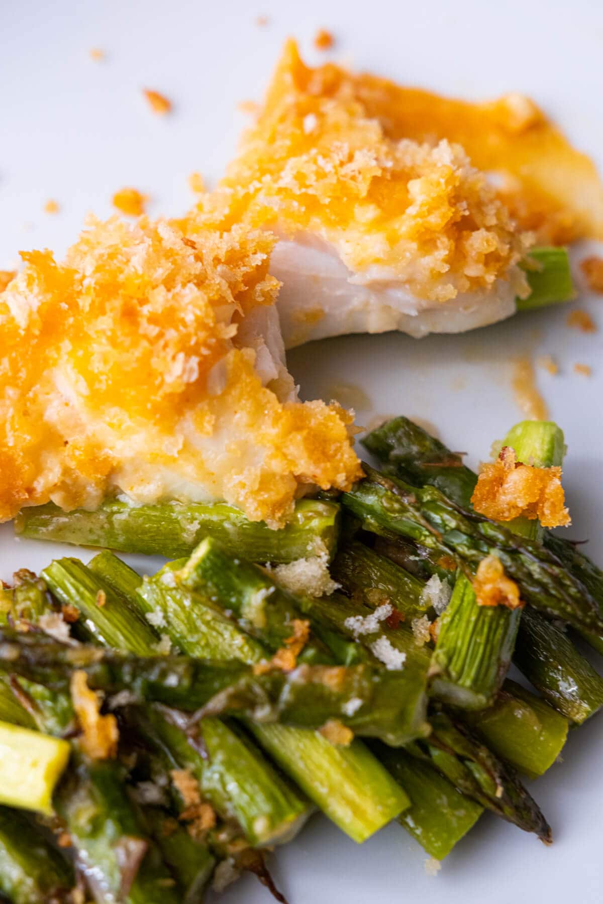 Close up on the tender sea bass fillet with crunchy panko atop baked asparagus. 