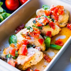 Bruschetta chicken topped with melting cheese, chopped tomatoes and basil leaves.