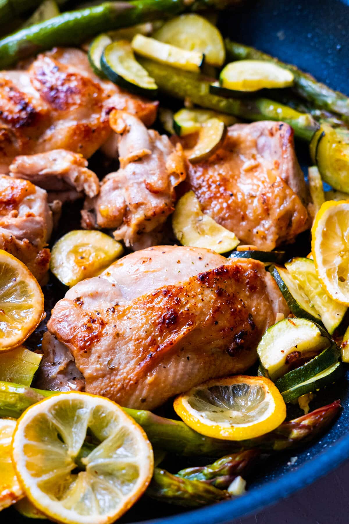 Baked Greek chicken in a skillet with vegetables. 