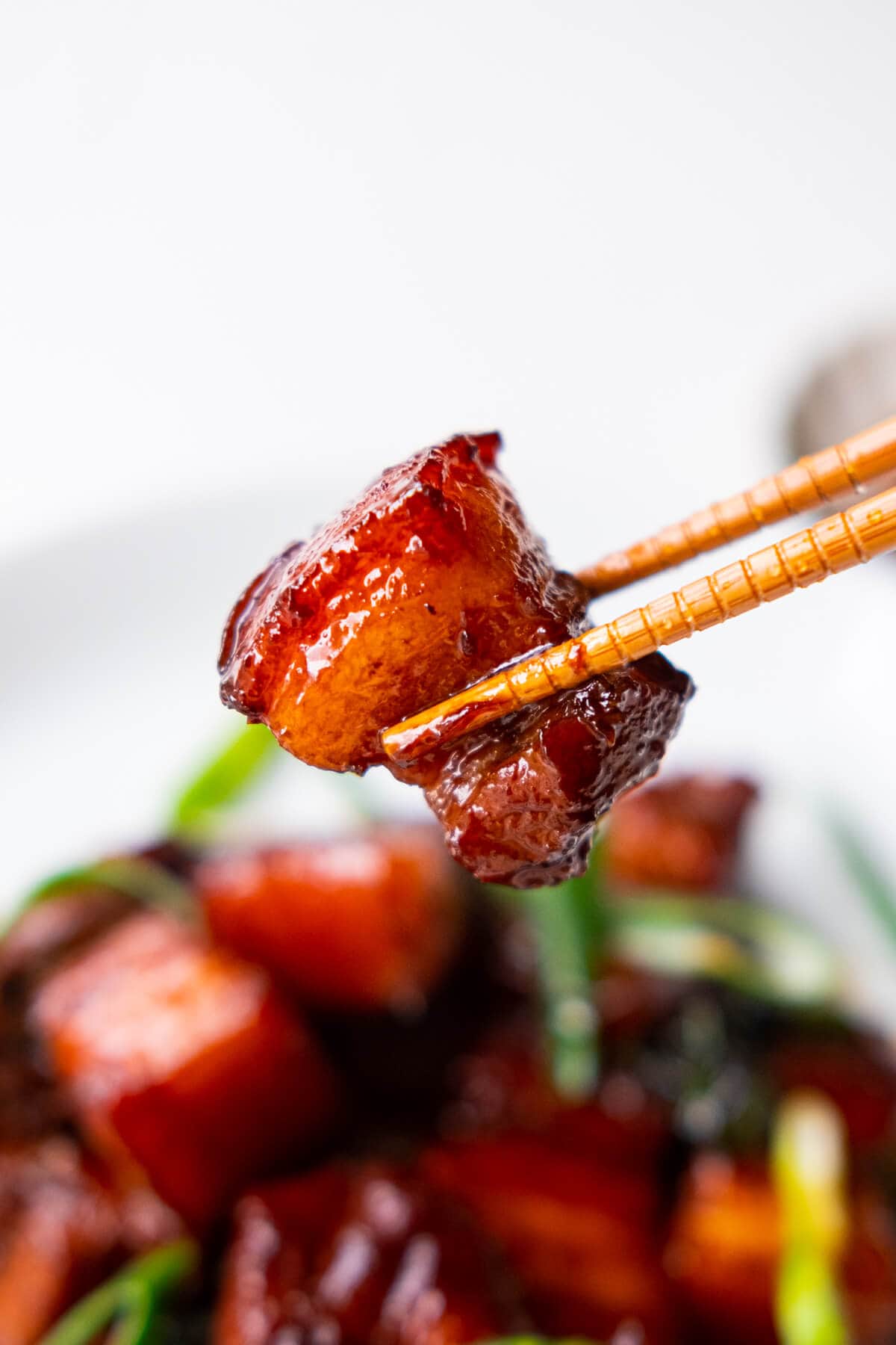 A piece of braised pork belly picked by a chopstick.