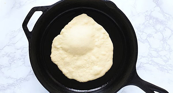 Making naan bread on a hot cast-iron skillet. 