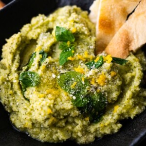 Parmesan and zucchini dip served in a platter with slices of Italian puff bread.