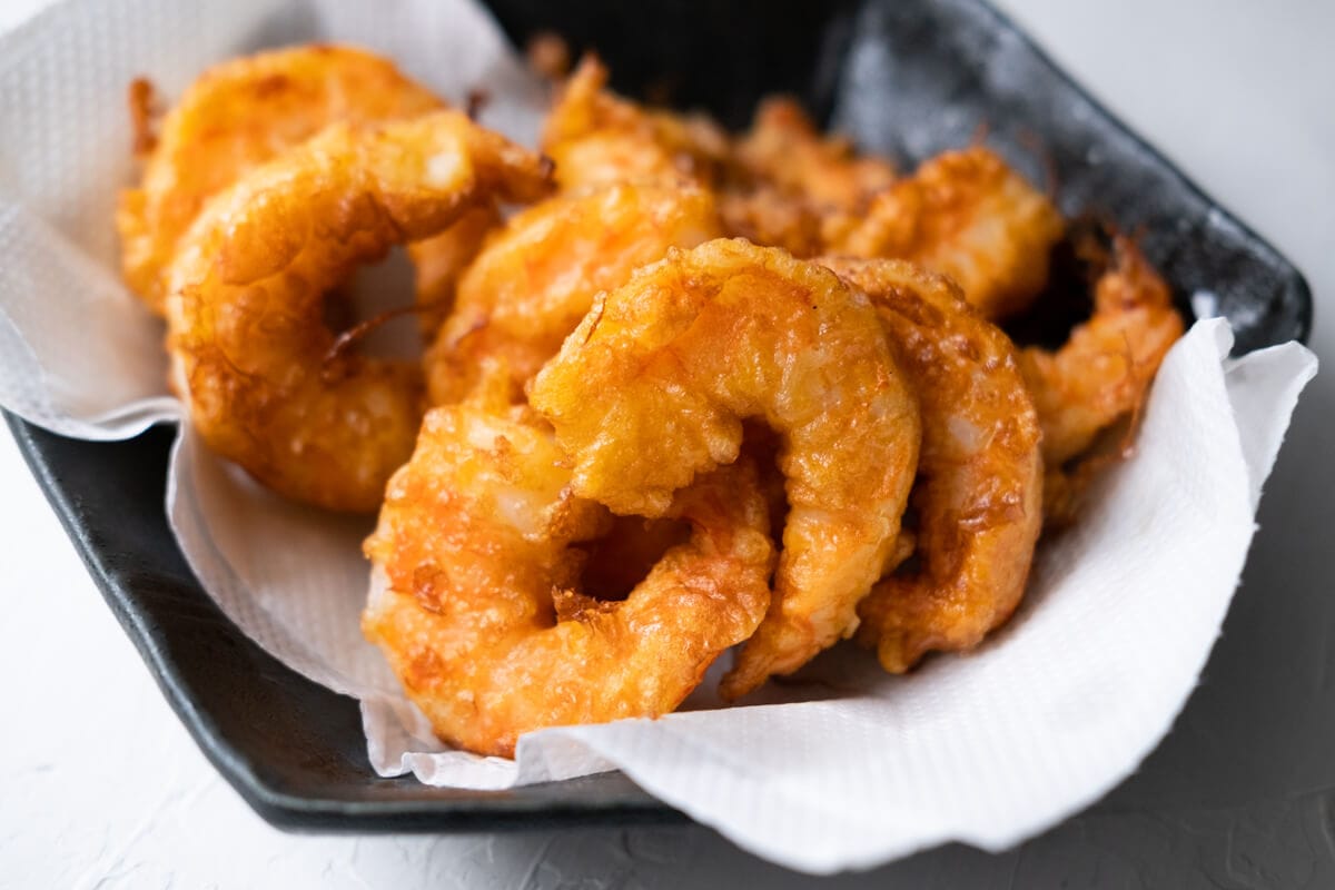 Deep-fried shrimp placed on a plate lined with paper towel. 