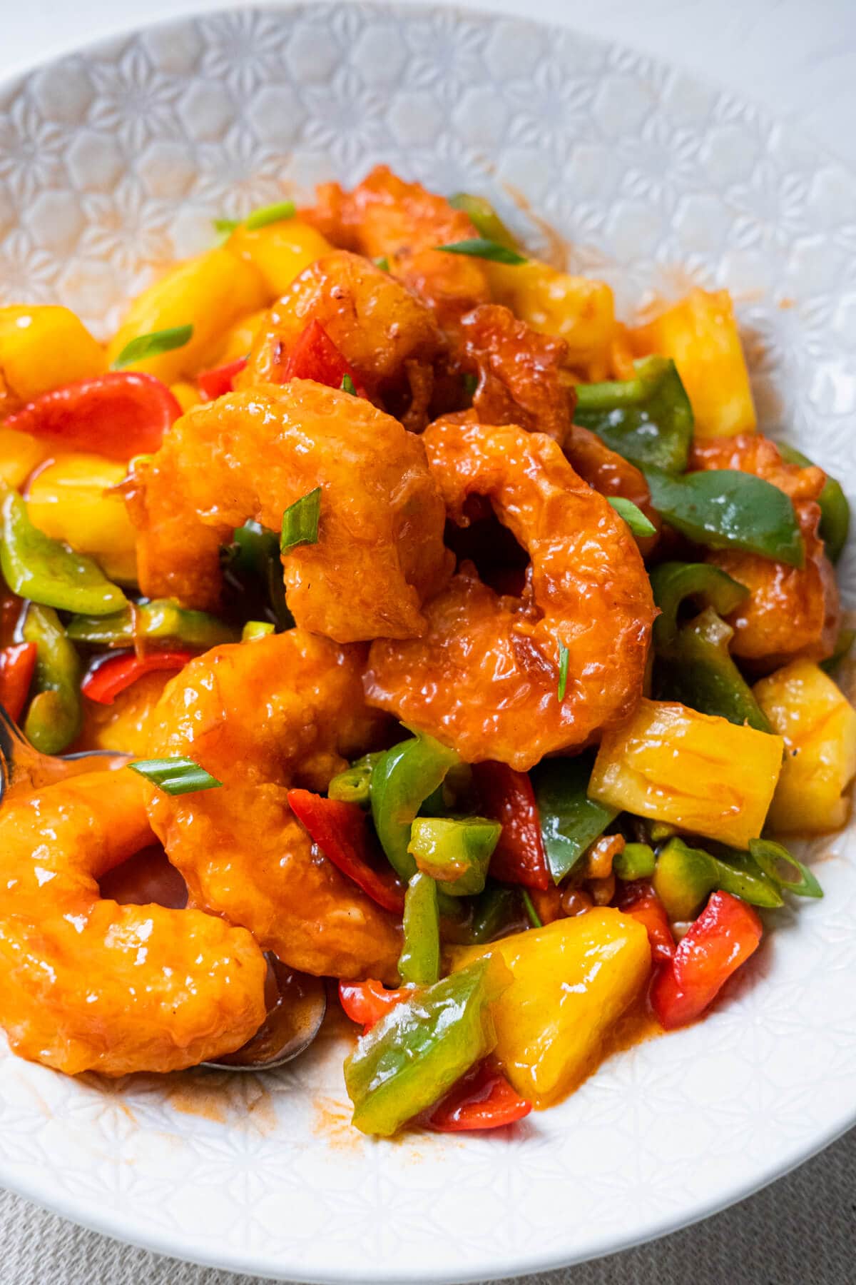 Sweet and sour shrimp lightly coated in red tomato sauce mixture and served together with small pieces of green and red bell pepper and pineapple. 