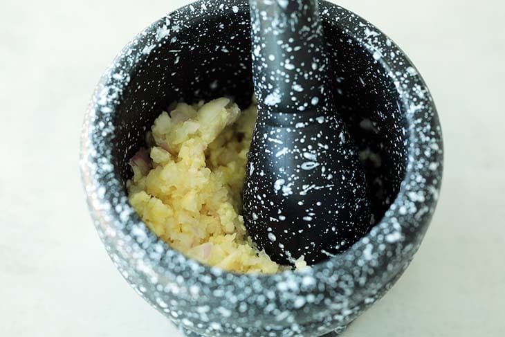 Pounding garlic with a mortar and pestle. 