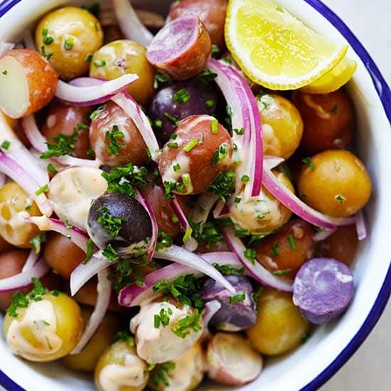 Baby potatoes salad garnished with chives and red onion. 