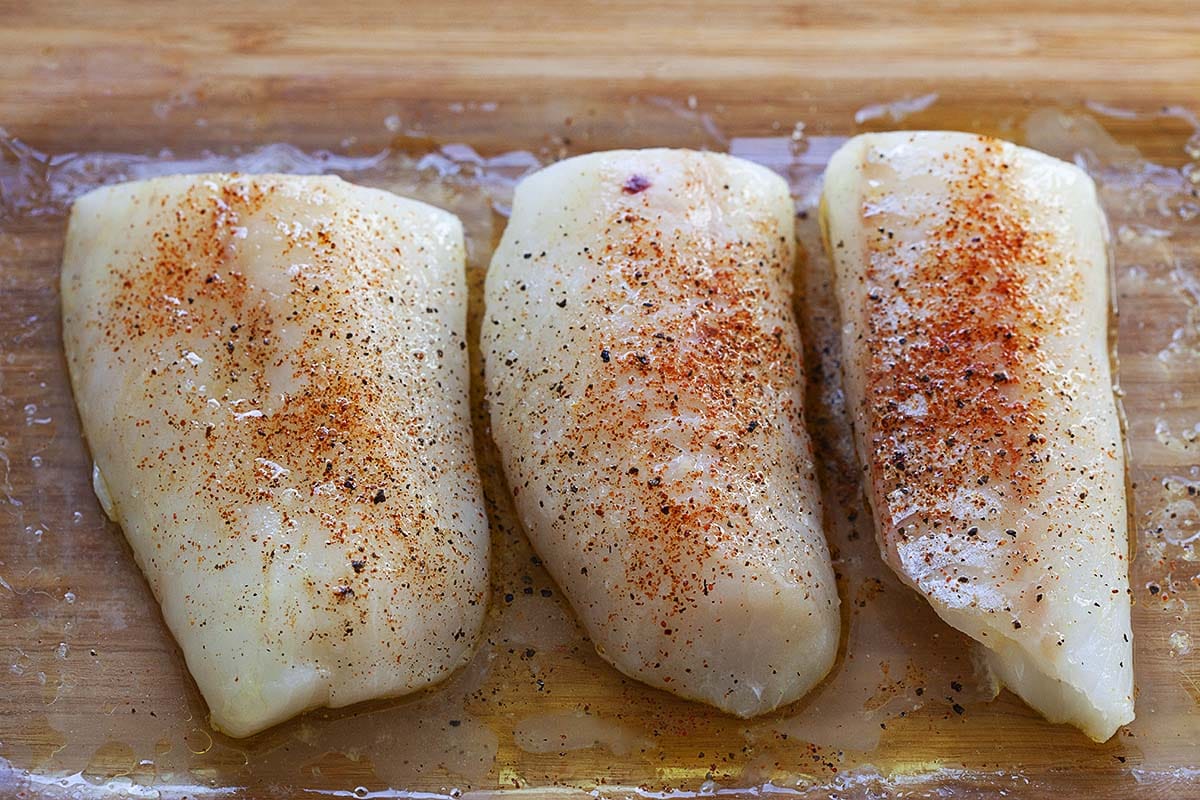 Cod fish fillets seasoned with lemon juice, salt and cayenne paper, ready to be baked. 