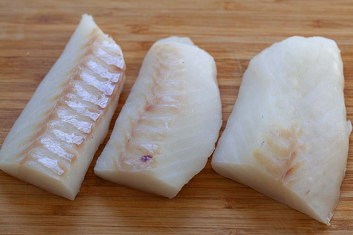 Frozen cod loins on a cutting board.