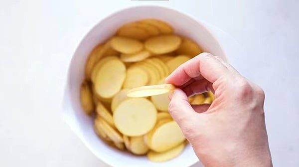This image shows the Yukon Gold Potatoes being cut into thin slices.