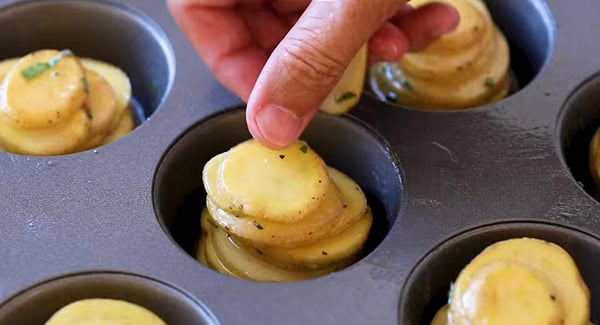 This image shows the sliced potatoes being laid into a baking tray.