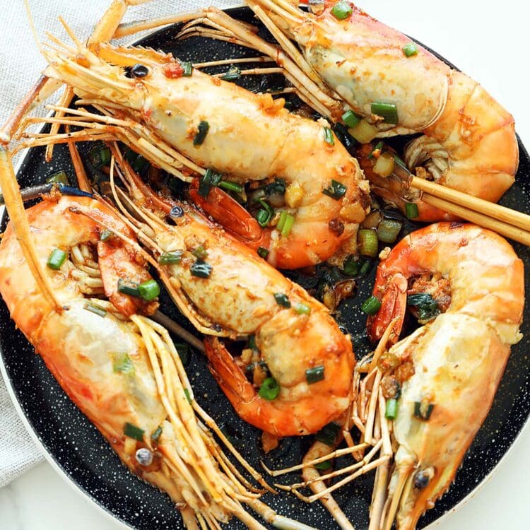 Pan Fried Prawns served on a plate topped with scallions.